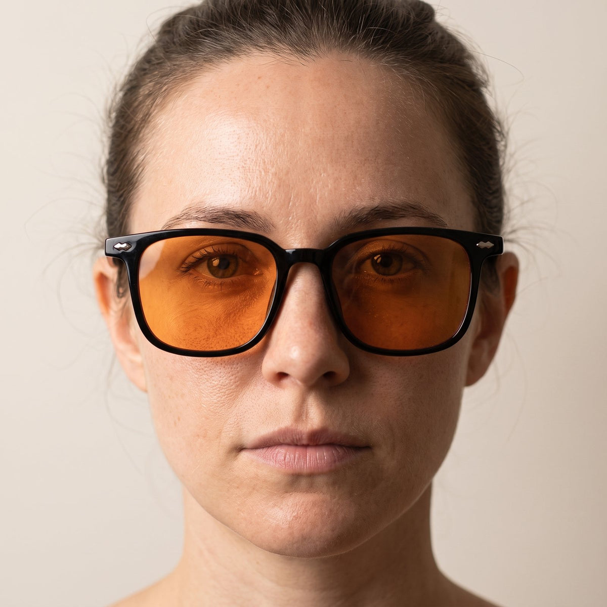A woman wearing Hueban SR Clarity glasses with black frames and amber lenses