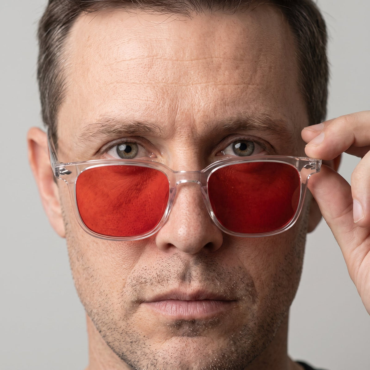 A man wearing Hueban SR Ember glasses with clear frames and red lenses