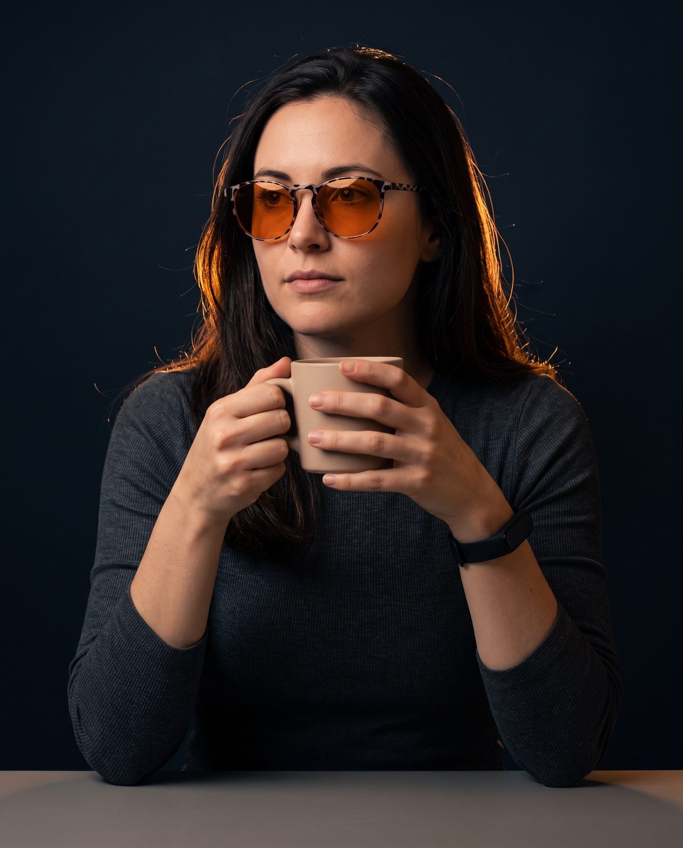 A woman holding a mug in the evening wearing Hueban SR glasses with amber lenses